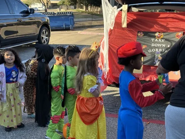 Children in costume gathered at a decorated trunk at a past Trunk or Treat
