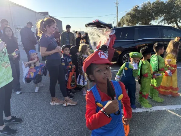 Children in costume lining up for treats at a past Trunk or Treat
