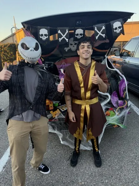 Two instructors in costume beside a decorated trunk at a past Trunk or Treat