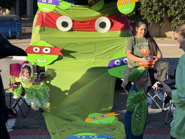 A trunk decorated with a Ninja Turtles theme, with a family in costume, at a past Trunk or Treat